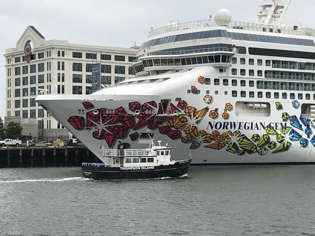 White hulled cruise ship features hull art resembling individual gem stones in deep red, orange, light green, and blue arranged by color. 