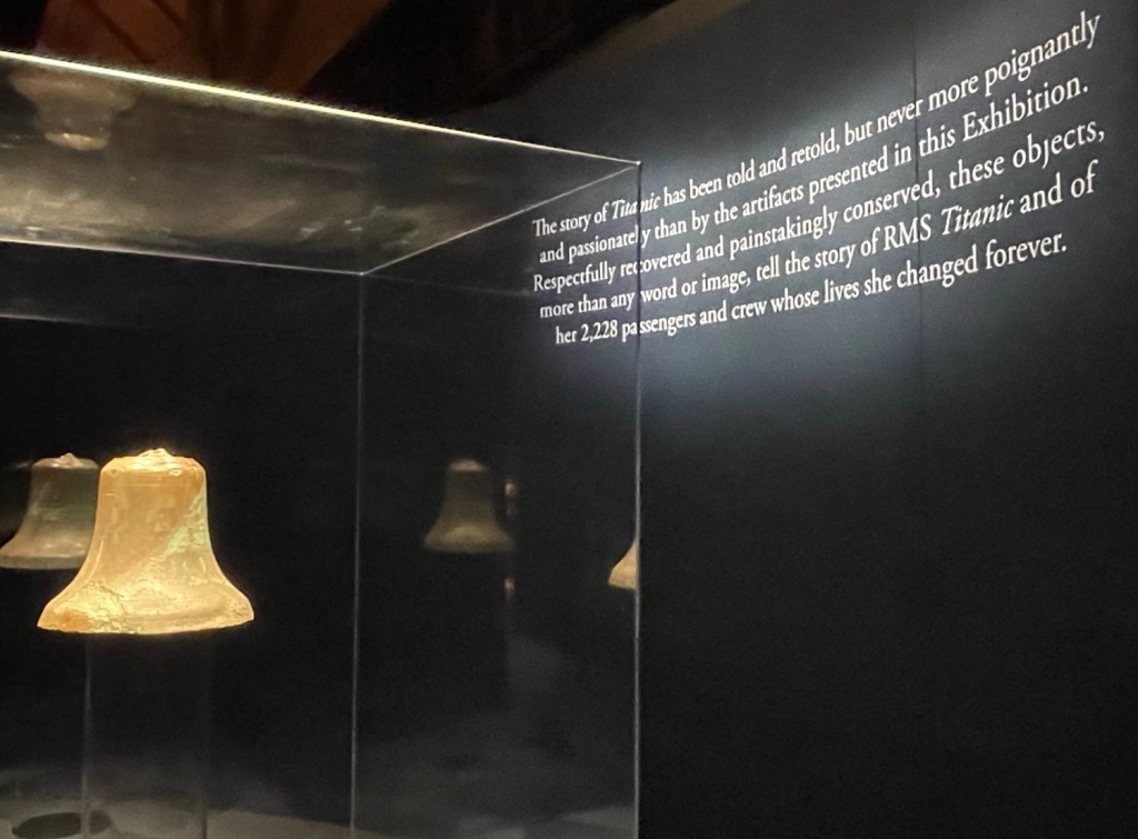 On a wall behind a salvaged bell are the words The story of Titanic has been told and retold, but never more poignantly and passionately than by the atifacts presented in this Exhibition. Respectfully recovered and painstakingly conserved, these objects, more than any word or image, tell the story of RMS Titanic and of her 2,228 passengers and crew whose lives she changed forever.