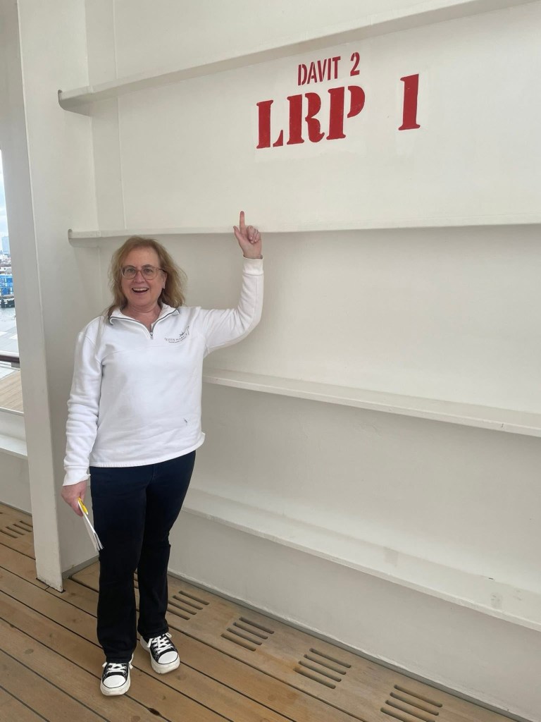 Lisa points to markings on a ships outer wall reading davit 2 L R P 1. 