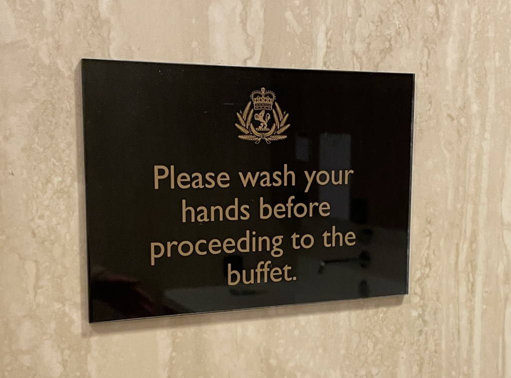 Sign on a marble wall reads please wash your hands before proceeding to the buffet 