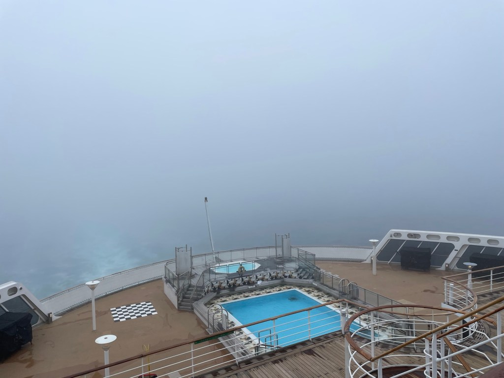 View off the back of a passenger ship with dense fog obscuring the ocean and sky. 