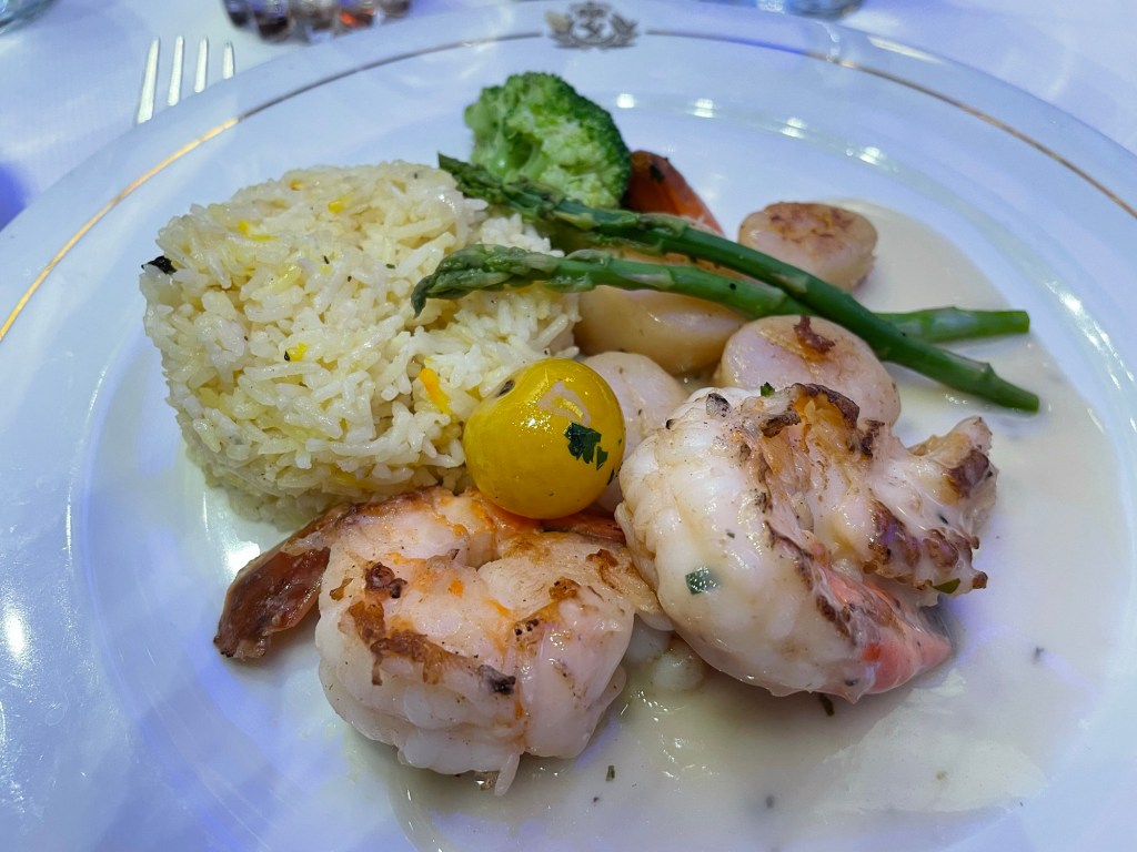 2 large grilled shrimp and 4 grilled scallops share a plate with a scoop of rice pilaf and broccolini 